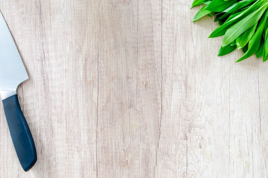 Chef's knife and fresh herbs on a wooden cutting board, how to prevent cuts in the kitchen