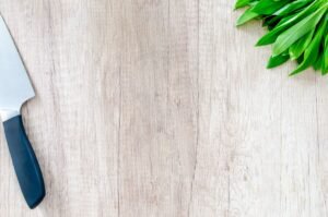 Chef's knife and fresh herbs on a wooden cutting board, how to prevent cuts in the kitchen