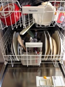 Loaded dishwasher rack with clean dishes and cutlery
