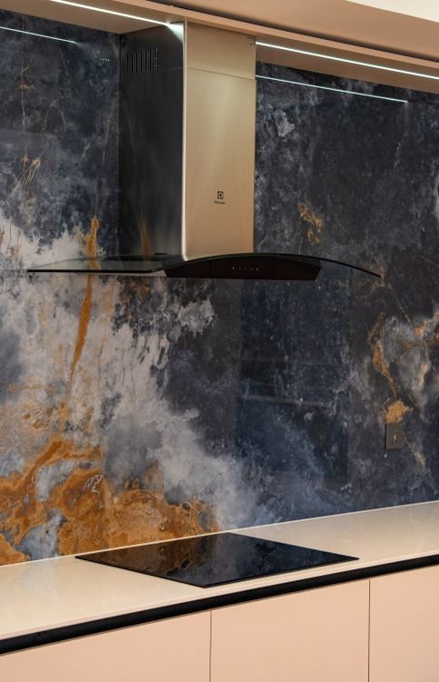 range hood installed above a gas range with marble backsplash