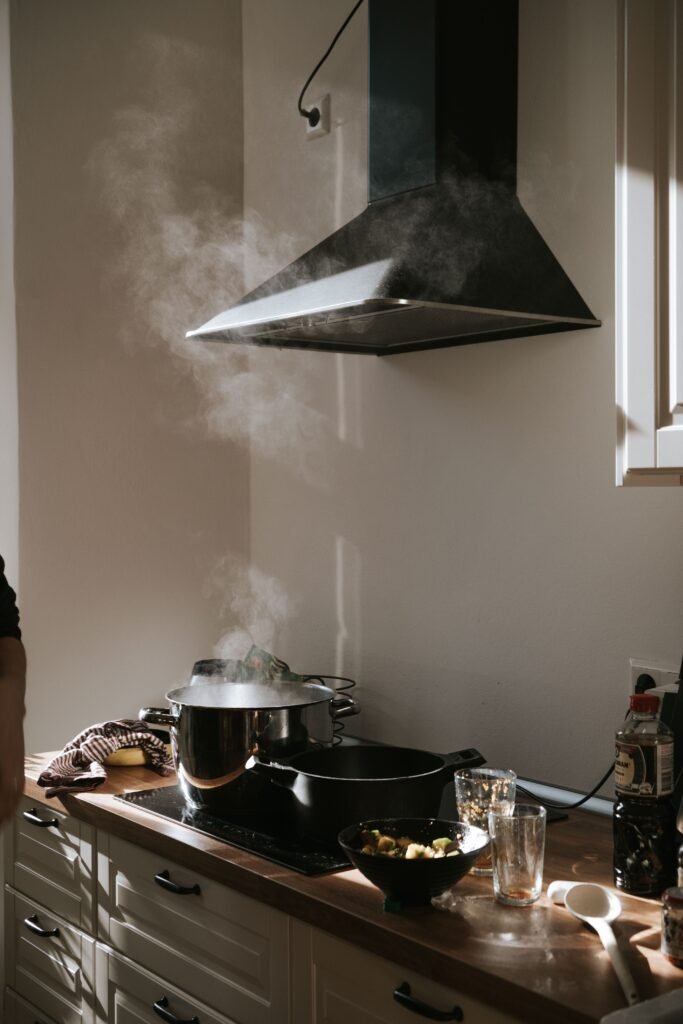 Sunlight in a modern kitchen with steam rising from pots under a range hood