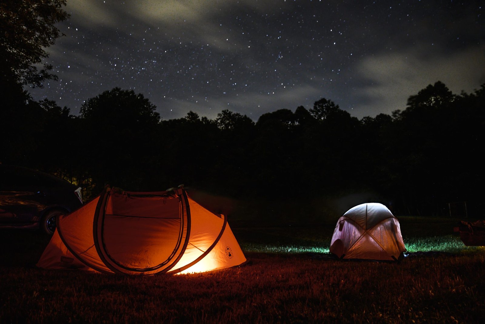 Illuminated tents at a campsite near wine country under a starry sky