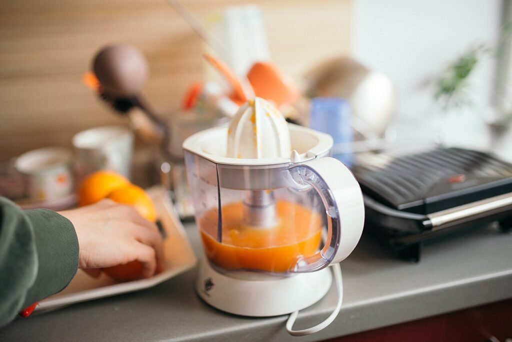 Fresh orange juice being prepared with a juicer in a home kitchen