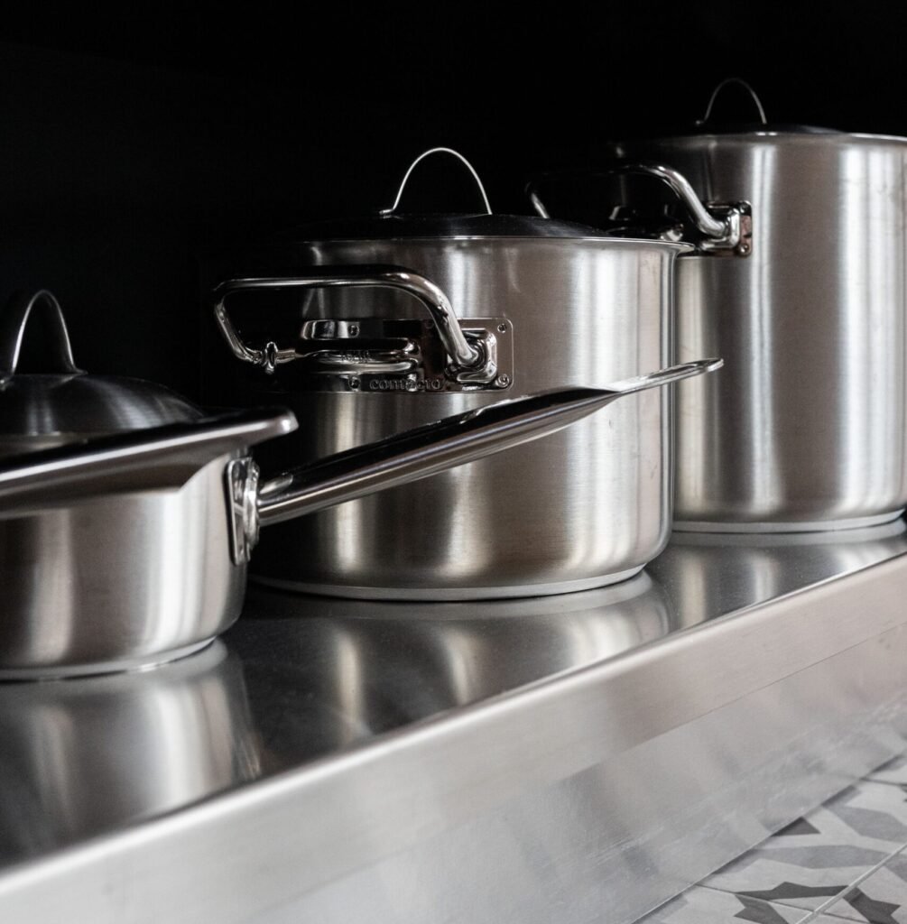 Stainless steel pots next to anodized cookware for a material comparison