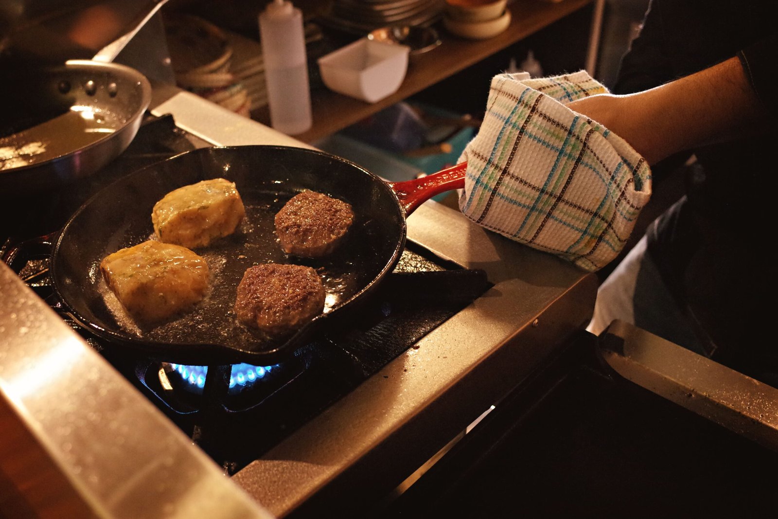 cast iron skillet cooking burgers on a gas stove