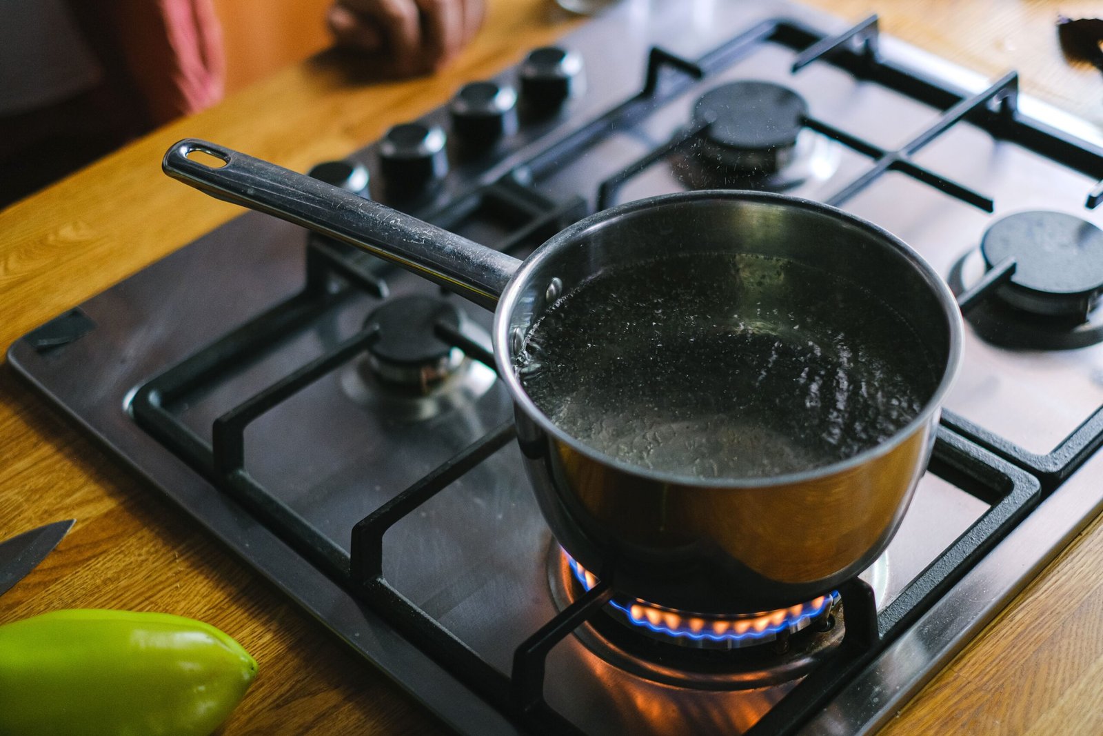 Stainless steel pot boiling water on a gas range burner in a kitchen