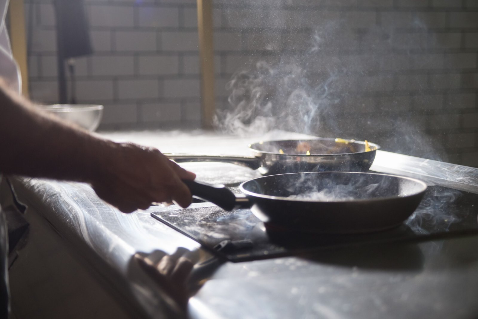 Chef sauteing food in a hard anodized frying pan on the stove