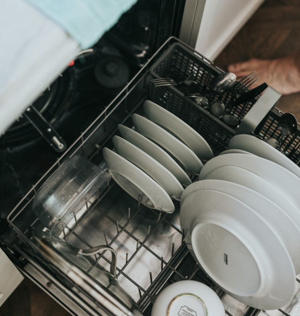 Open dishwasher with a clean white plate, illustrating how to get dish soap out of a dishwasher
