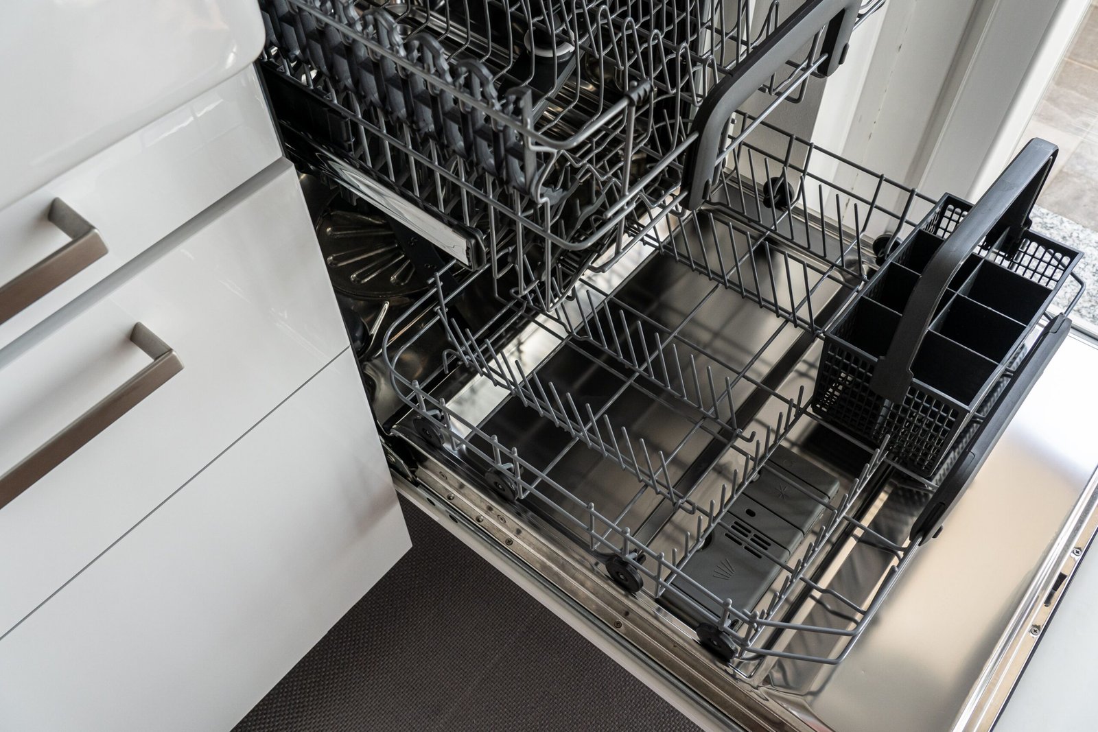 empty freestanding dishwasher open and ready for installation in a modern kitchen