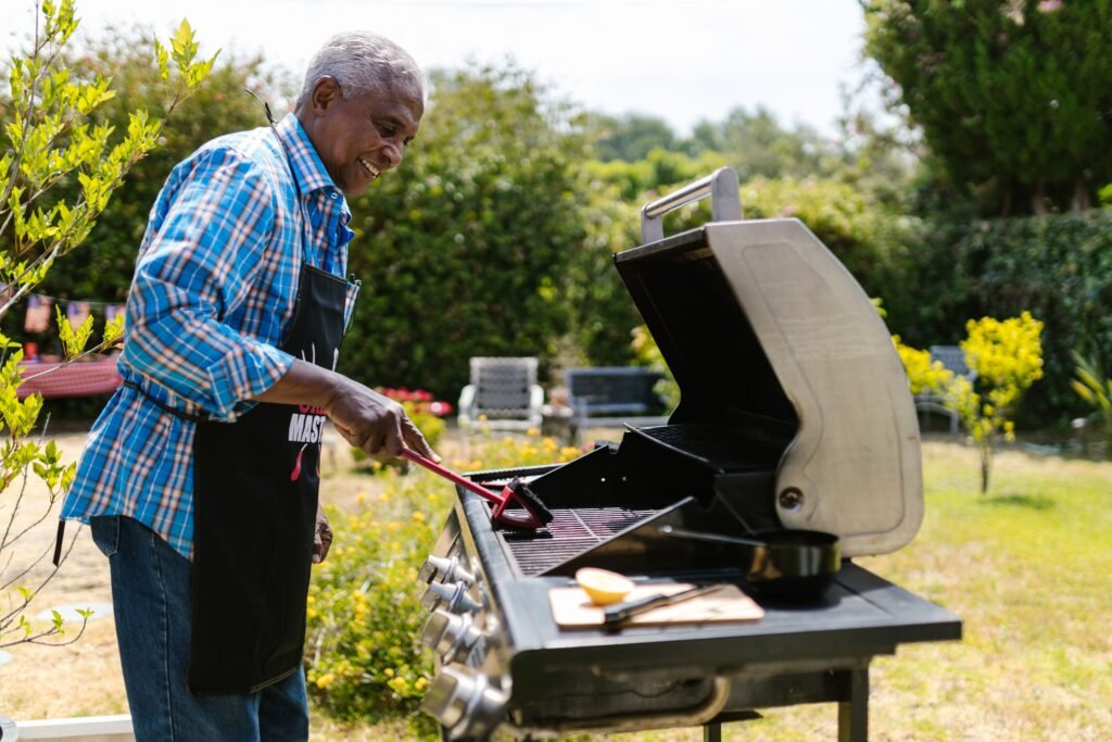 Man tending to a gas grill outdoors as part of routine grill maintenance