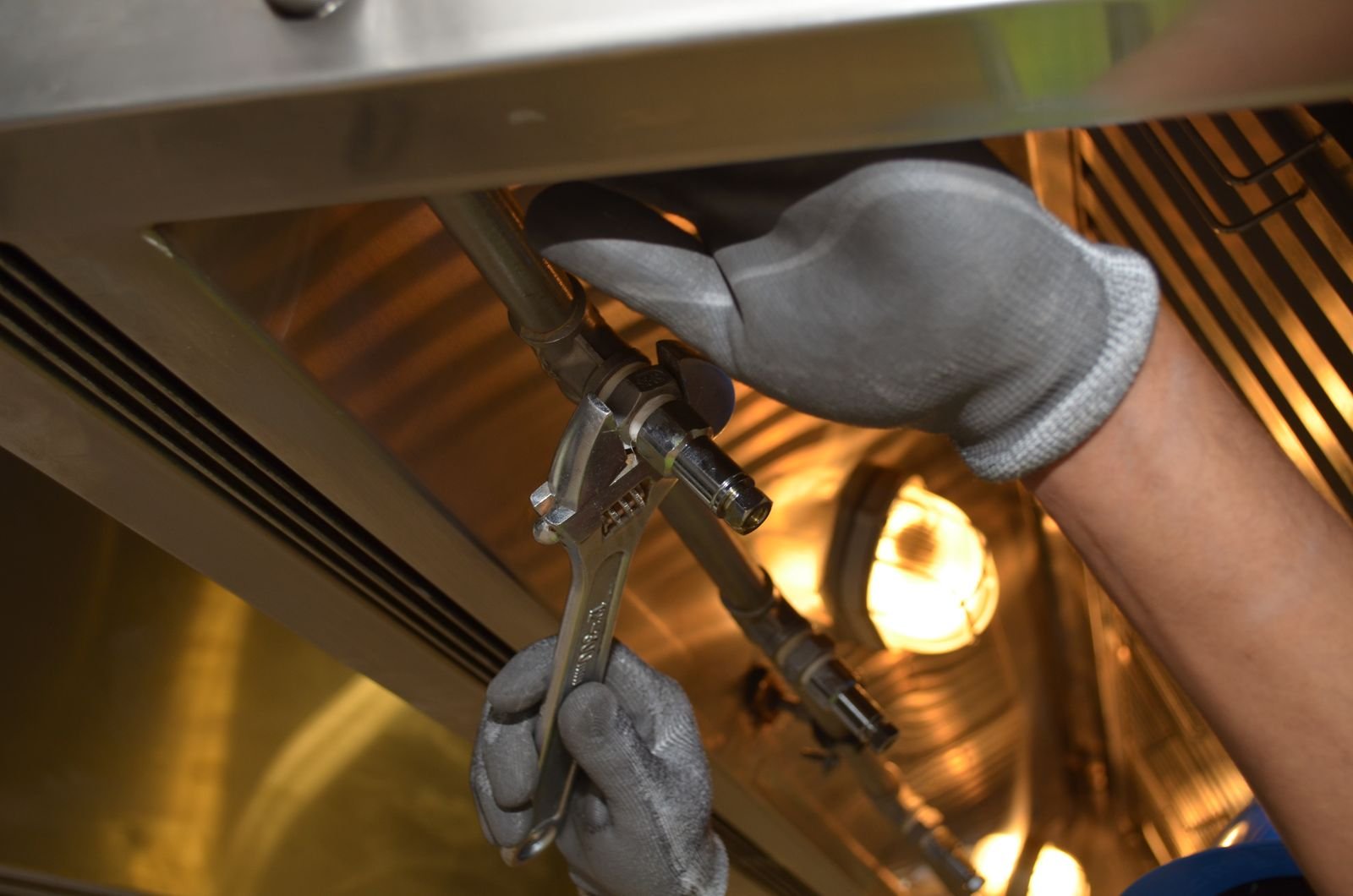 Disconnect a gas range worker using a spanner to fix a pipe fitting indoors