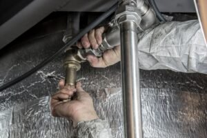 hands using a wrench on a steel pipe fitting