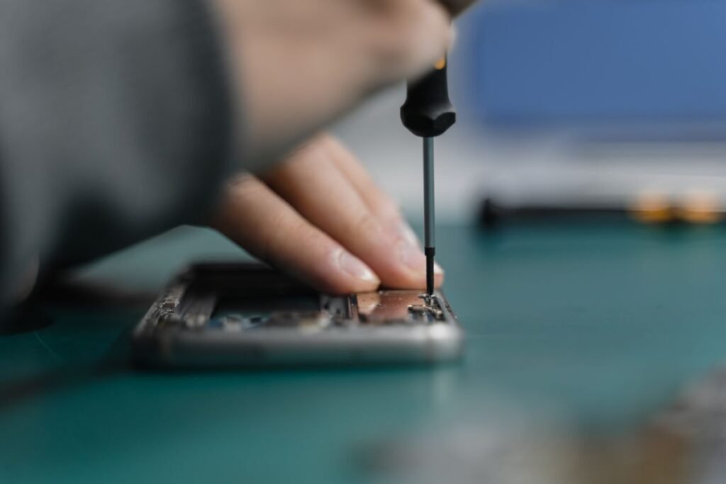 A hand using a screwdriver to work on an appliance component