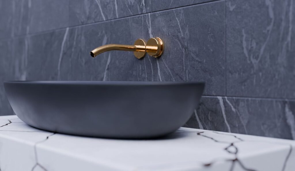 bathroom vessel sink paired with a gold wall-mounted faucet on a marble slab
