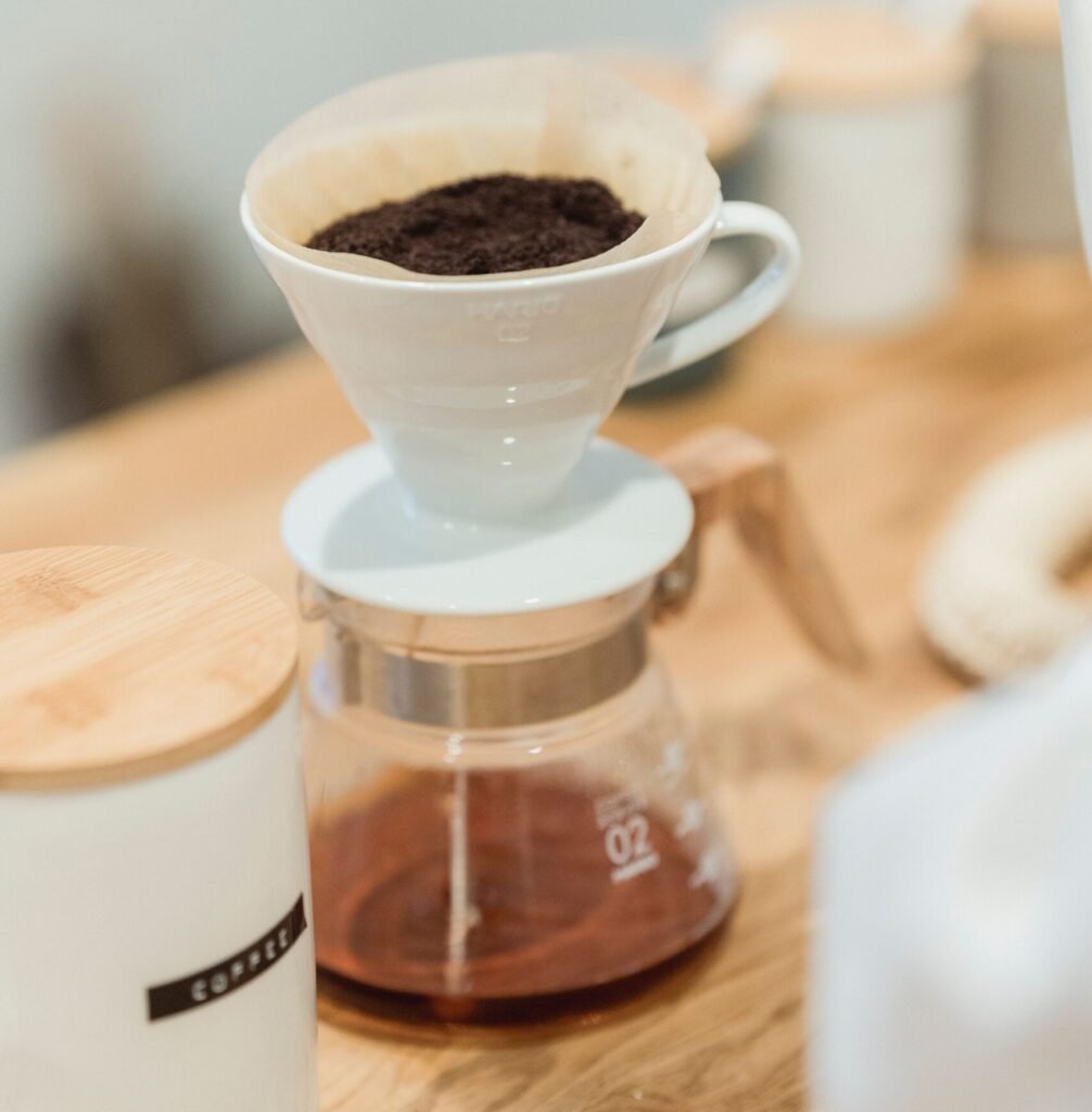 ceramic pour-over coffee dripper with paper filter on a glass carafe