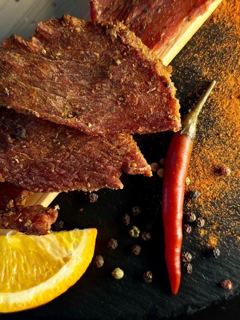 sliced dried meat jerky with spices on a board