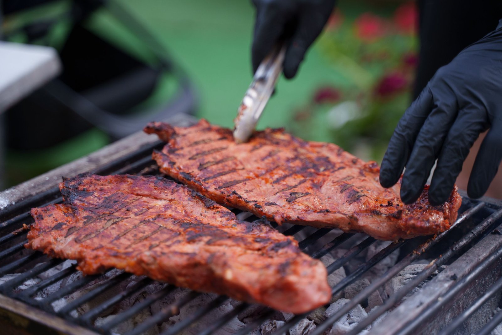 Steaks grilling and being flipped on an outdoor barbecue