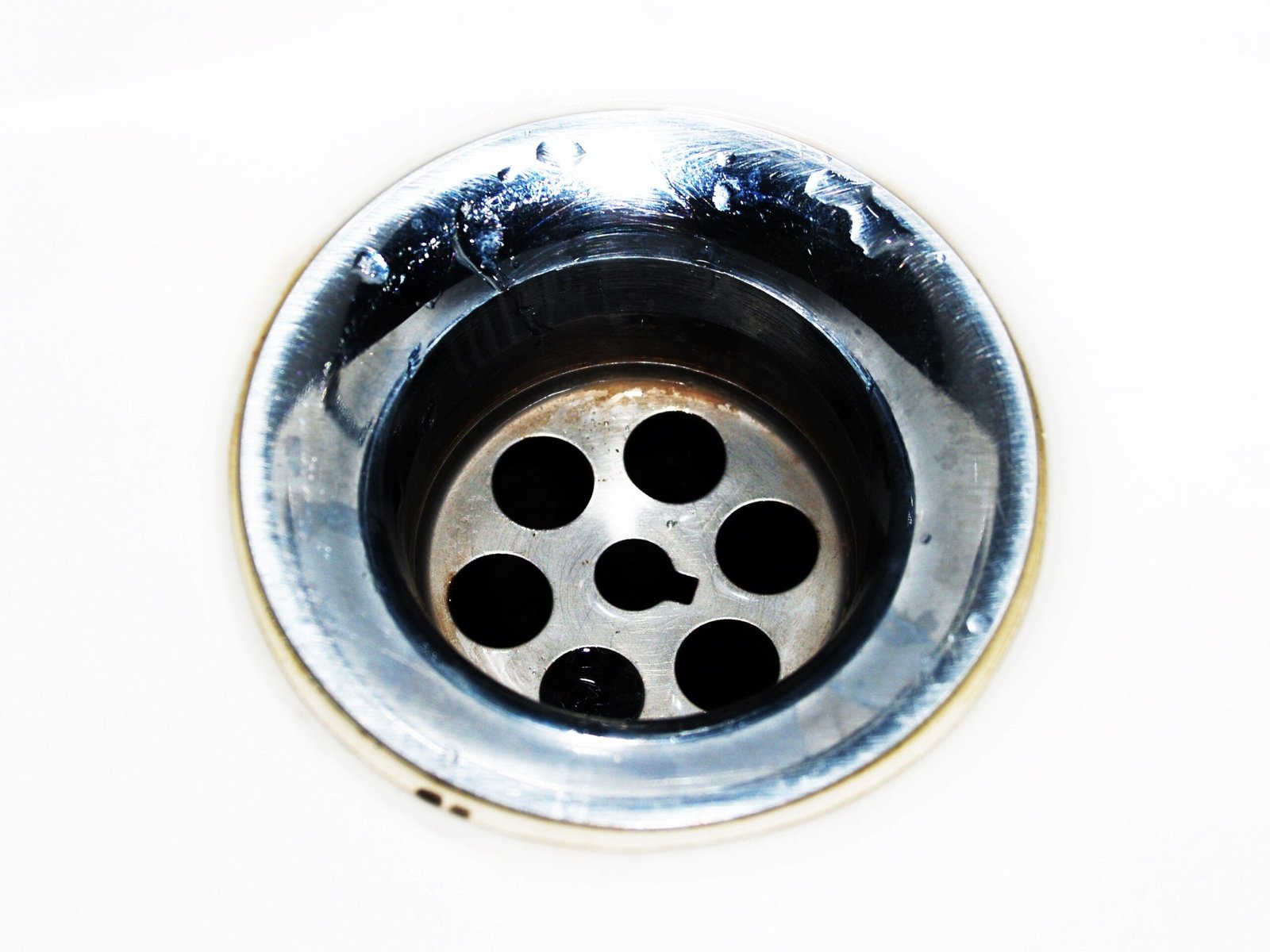 Close-up of a stainless steel kitchen sink drain with standing water