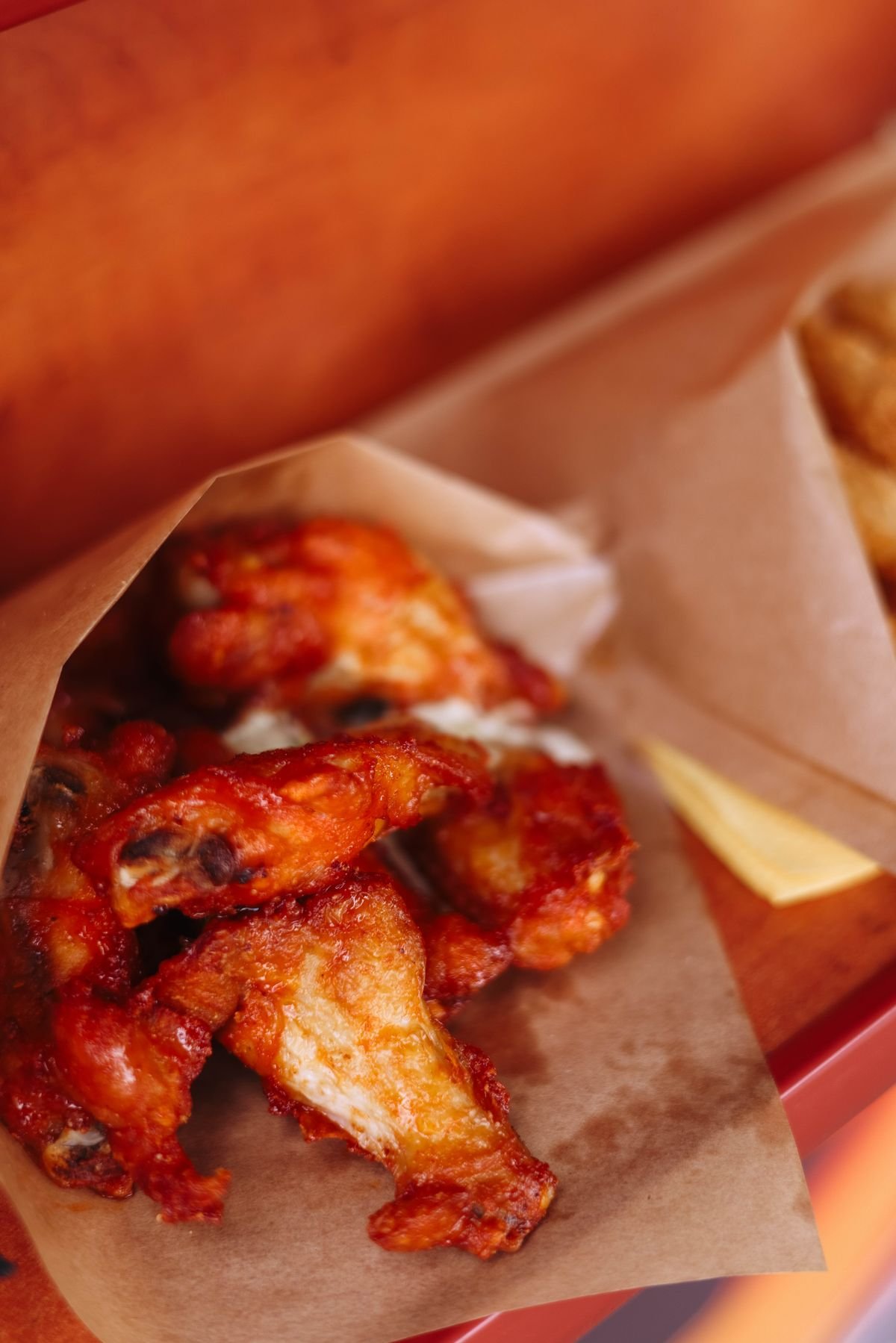 Crispy buffalo chicken wings served on parchment paper