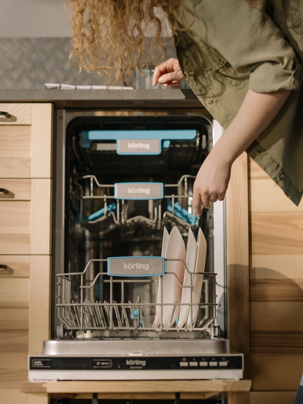 Person loading a dishwasher that drains through the garbage disposal