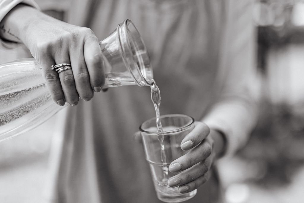 pouring clean filtered drinking water from a carafe into a glass