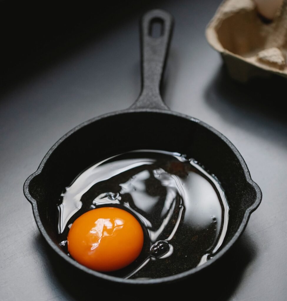 cracking a raw egg into a cast iron skillet cracking a raw egg into a cast iron skillet