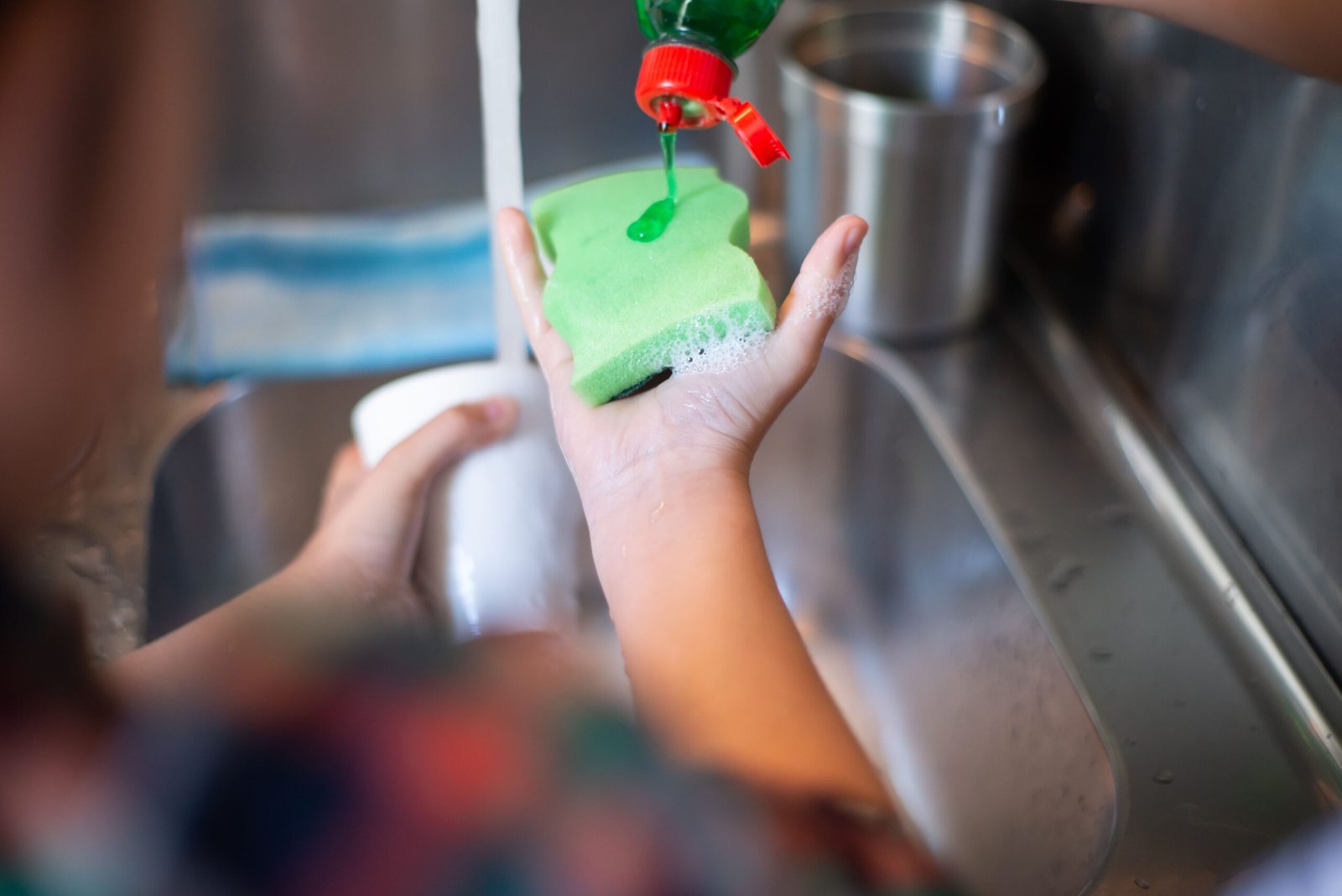 liquid dish soap being poured onto a sponge for cleaning kitchen tools