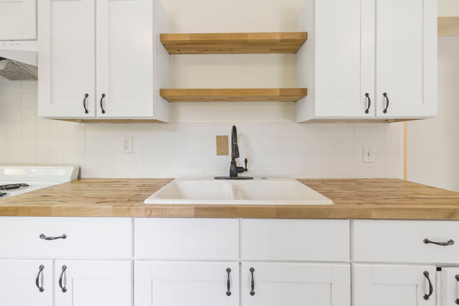 Modern kitchen with white cabinets and warm wood butcher block countertops