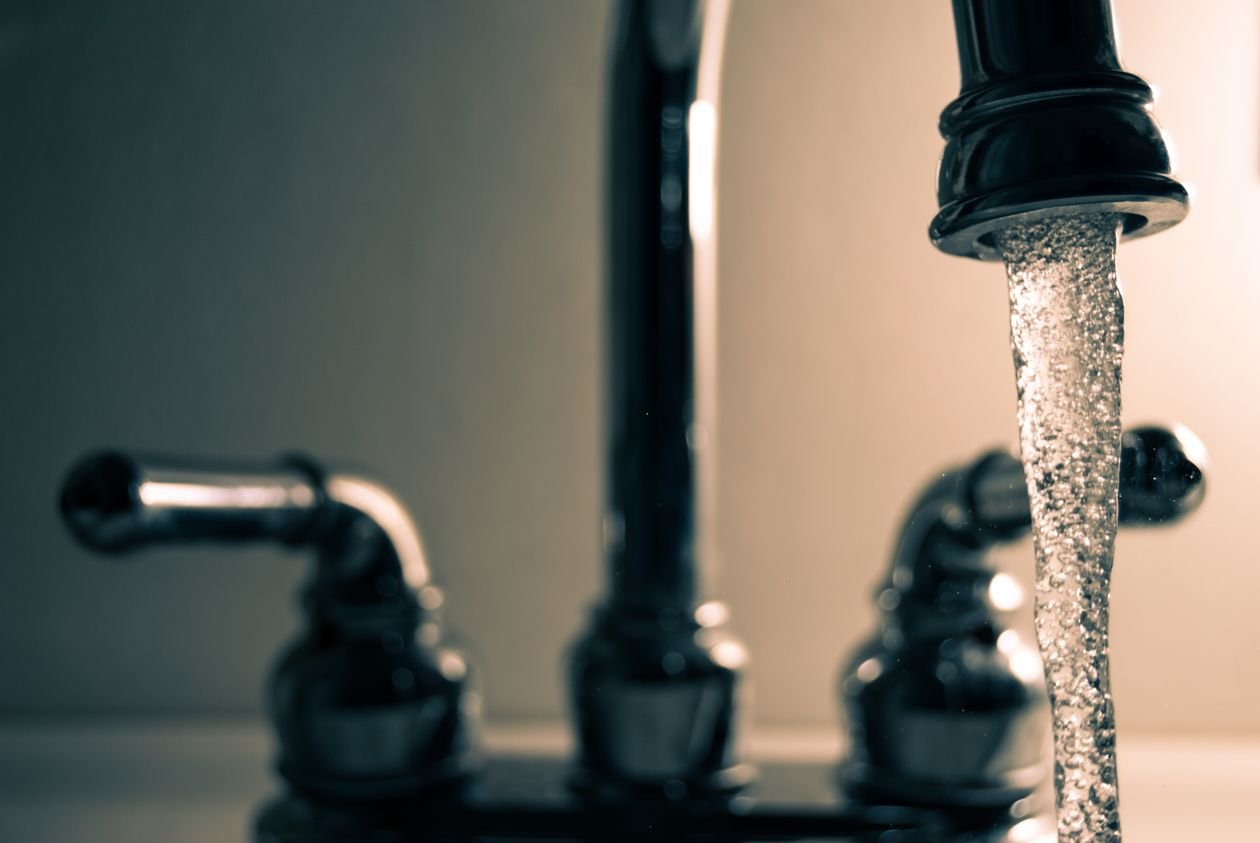 Hard tap water flowing from a steel kitchen faucet