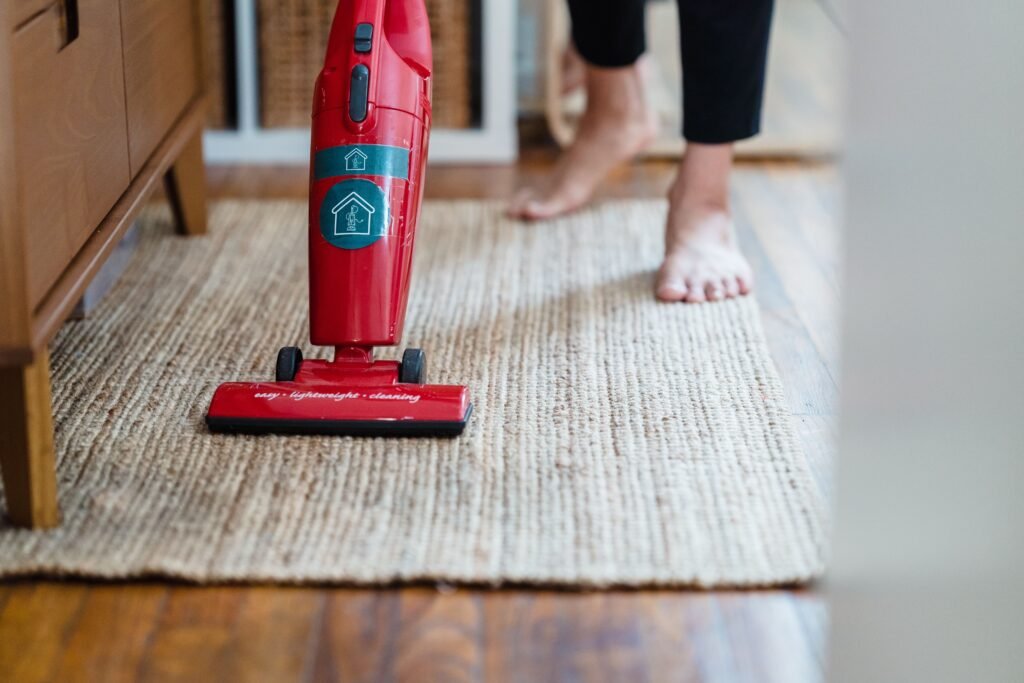 person vacuuming a carpet at home after cleaning