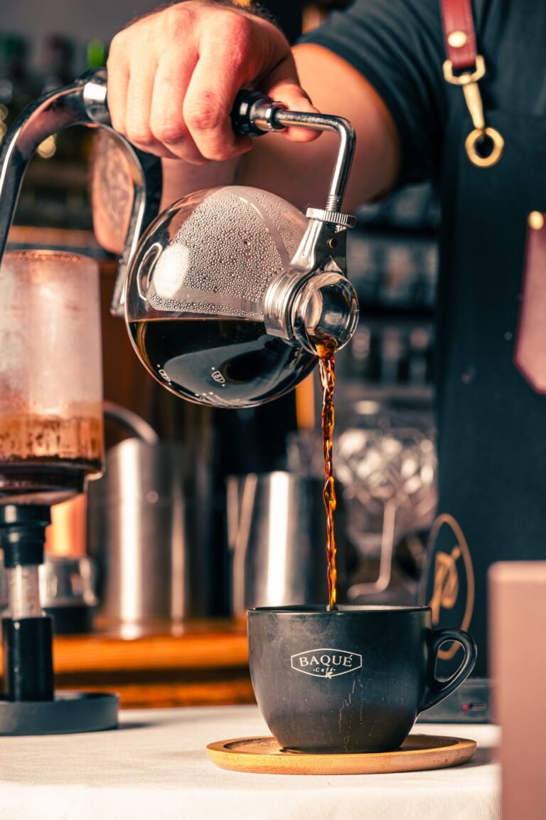pouring freshly brewed coffee from a glass carafe into a cup